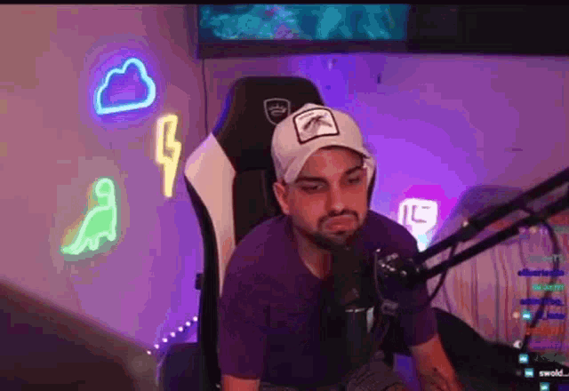 a man is sitting in a chair in front of a microphone in a room with neon lights .
