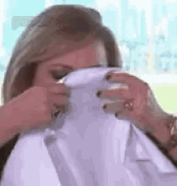 a woman is covering her face with a white shirt and a tie .