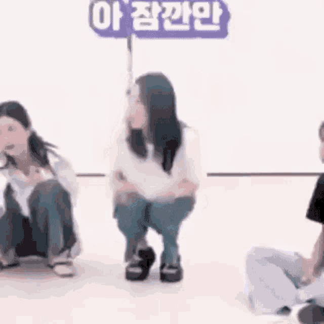 a group of women are squatting down on the floor in a room .