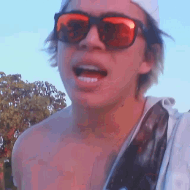 a young man wearing sunglasses and a white hat is making a funny face