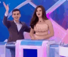 a man in a suit and a woman in a strapless dress are standing next to each other on a stage .