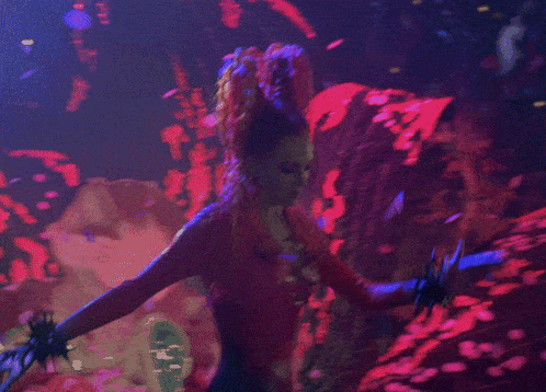a woman with red hair is standing in a dark room with purple lights
