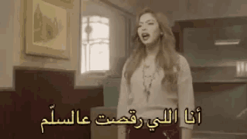 a woman singing in a room with arabic writing on the wall .