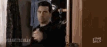 a man in a suit is standing in front of a closet .