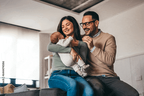 a man and woman are sitting on a couch with a baby