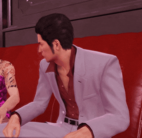 a man in a white suit sits on a red chair