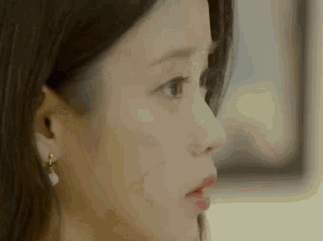 a close up of a woman 's face wearing earrings and looking at something .