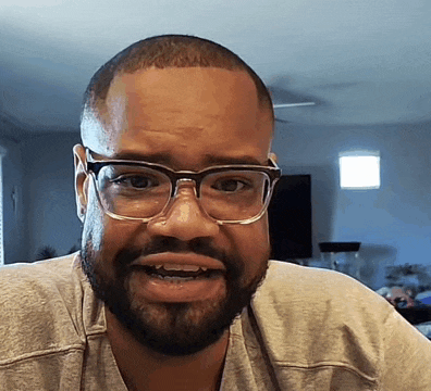 a man with a beard wearing glasses and a grey shirt
