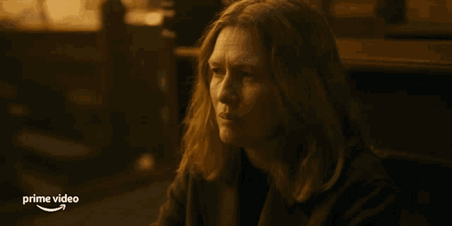 a woman with long hair is sitting in front of a sign that says " prime video "