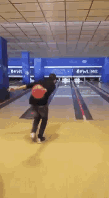 a man is throwing a bowling ball in a bowling alley .