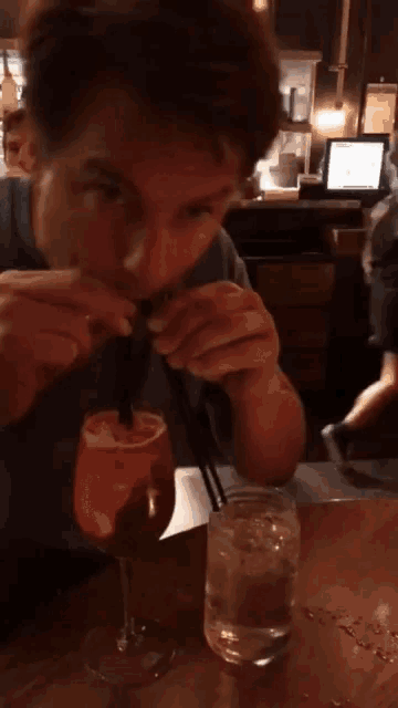 a man is drinking through a straw from a wine glass