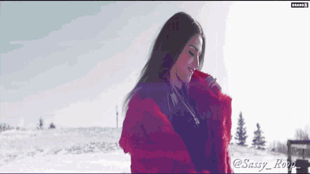 a woman in a red fur coat is standing in the snow with the name sassy rope on the bottom