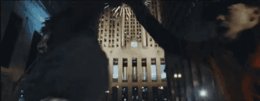 two men are standing next to each other in front of a building at night