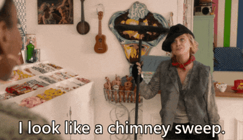 a woman in a black hat is holding a chimney sweep