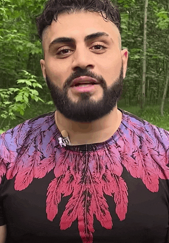 a man with a beard is wearing a feathered shirt
