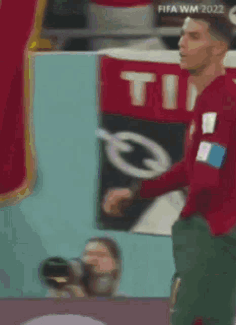 a soccer player is standing in front of a banner that says fifa wm 2022
