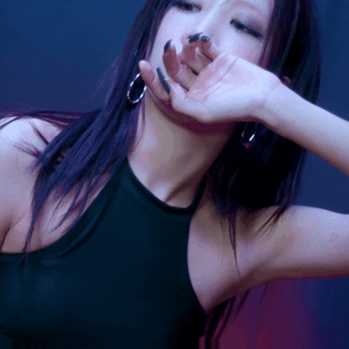 a woman covering her mouth with her hand while wearing a black tank top