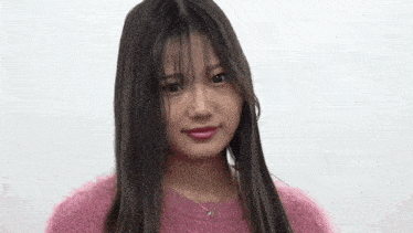a woman with long hair is wearing a pink sweater and a necklace .