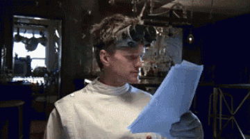 a man wearing a lab coat and goggles is reading a piece of paper