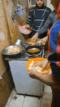 a group of men are preparing food on a stove top