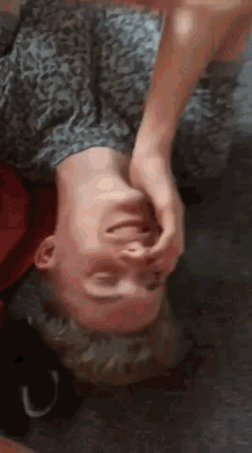 a young man is laying upside down on the floor making a face .