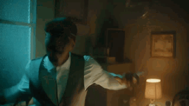 a man in a suit and hat is standing in a dark room .