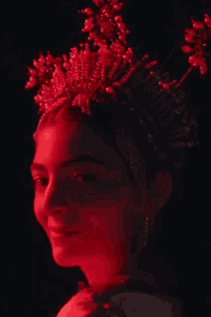 a woman with a crown on her head is lit up in red