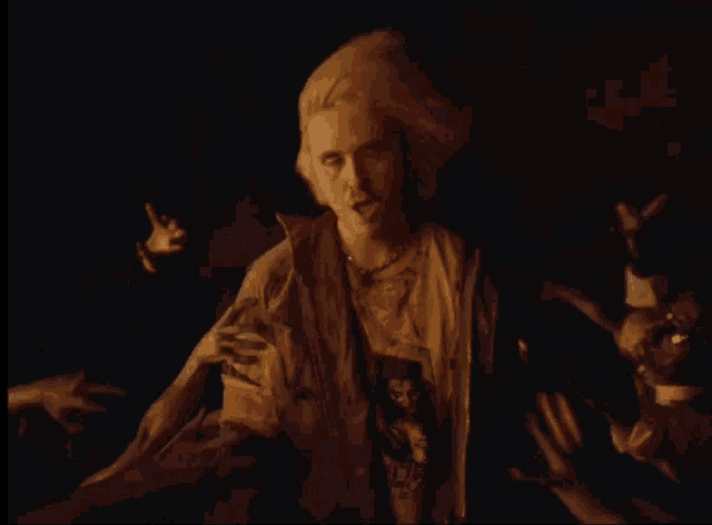 a man in a t-shirt with a picture of a man on it is surrounded by zombie hands