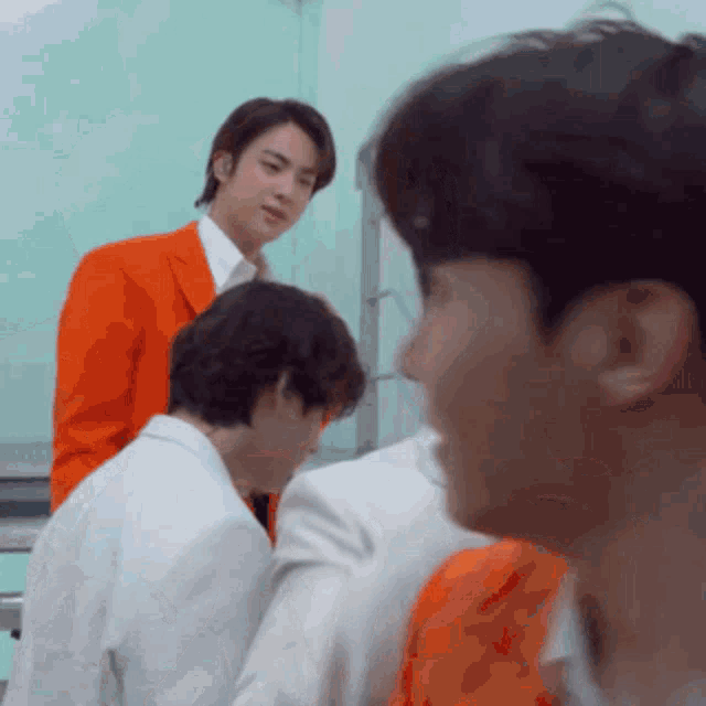 a man in an orange suit is standing next to a man in a white suit .