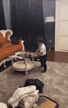 a little boy is standing in a living room next to a suitcase and a coffee table