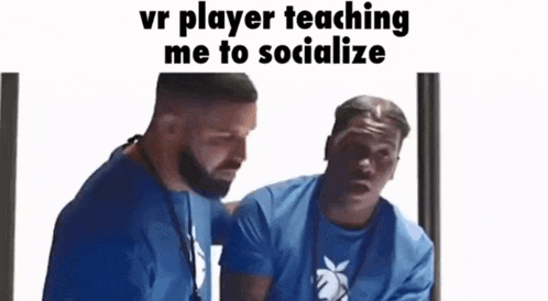two men in blue shirts are sitting next to each other and one of them is teaching the other how to socialize .