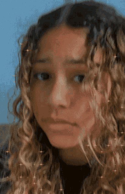 a young girl with curly hair is making a funny face