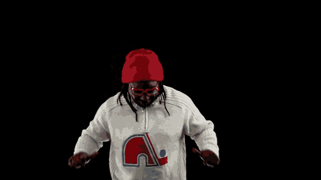 a man wearing a red hat and sunglasses is wearing a sweater with the letter a on it