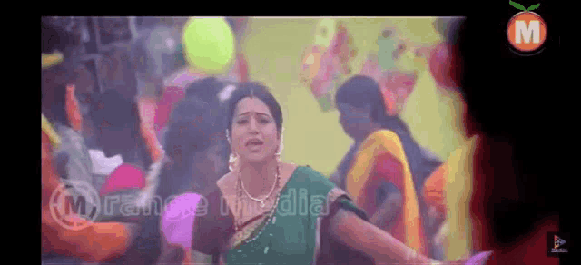 a woman in a green sari is dancing in front of a crowd