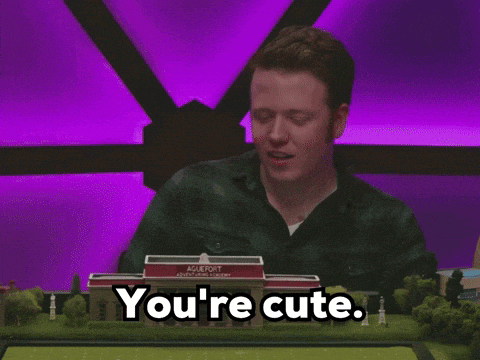 a man sitting in front of a model of a building that says ' you 're cute '