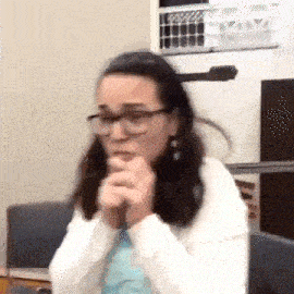 a woman wearing glasses is praying with her hands folded in front of her face