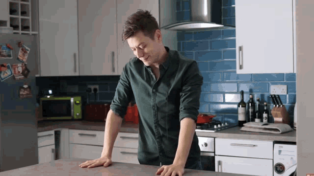 a man in a green shirt is standing in a kitchen with a lg washer and dryer