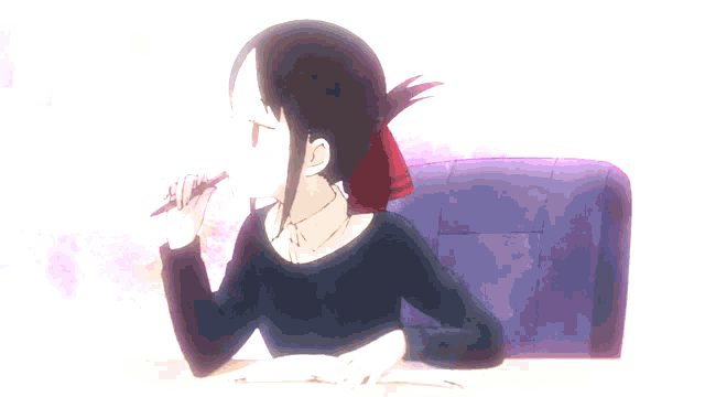 a girl is sitting at a desk with a book and a pen in her hand
