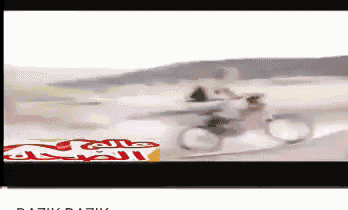 a blurred image of a man riding a motorcycle with a red bull logo in the background