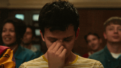 a young man covering his nose with his hand in front of a crowd