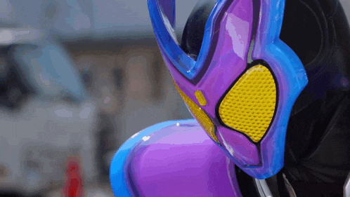 a purple and blue mask with a yellow eye