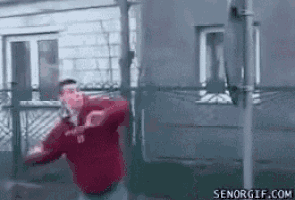 a man in a red shirt is dancing in front of a building with senorgif.com in the corner