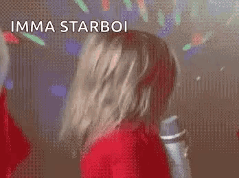 a little girl is singing into a microphone and making a funny face .