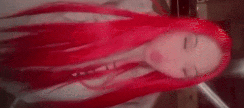 a woman with long red hair is laying down with her eyes closed in a red room .