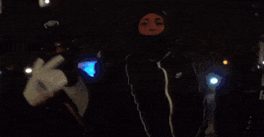 a group of people wearing masks are standing in a room .