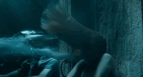 a woman in a white shirt is swimming in a dark room