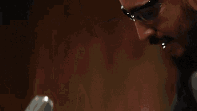 a man wearing safety glasses is holding a hammer in his hand .