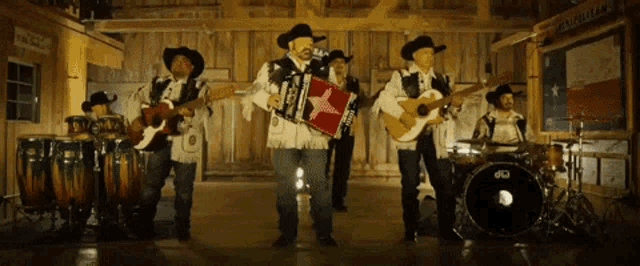 a group of men in cowboy hats are playing instruments in front of a drum set