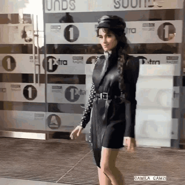 a woman in a black dress is walking in front of a building with the number 1 on it