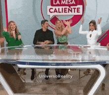 a group of people are sitting at a table with a sign that says la mesa caliente behind them